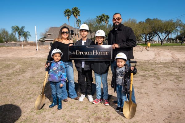 Family over lot holding #DreamHome sign