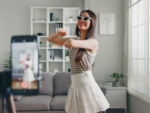 A young woman dancing and taking a picture of herself in a living room
